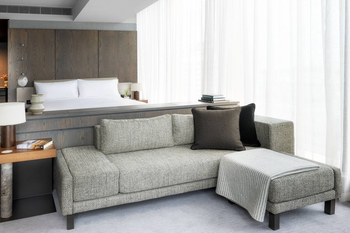 Ein modernes Hotelzimmer mit Bett, Sofa, Nachttisch und Lampe.