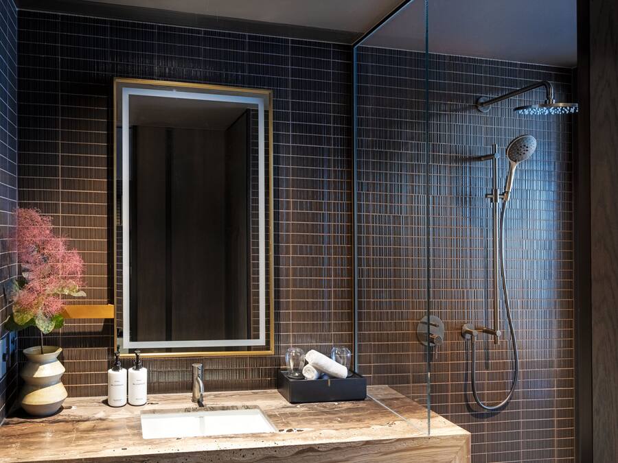 A modern bathroom with a large mirror, a sink, and a shower.