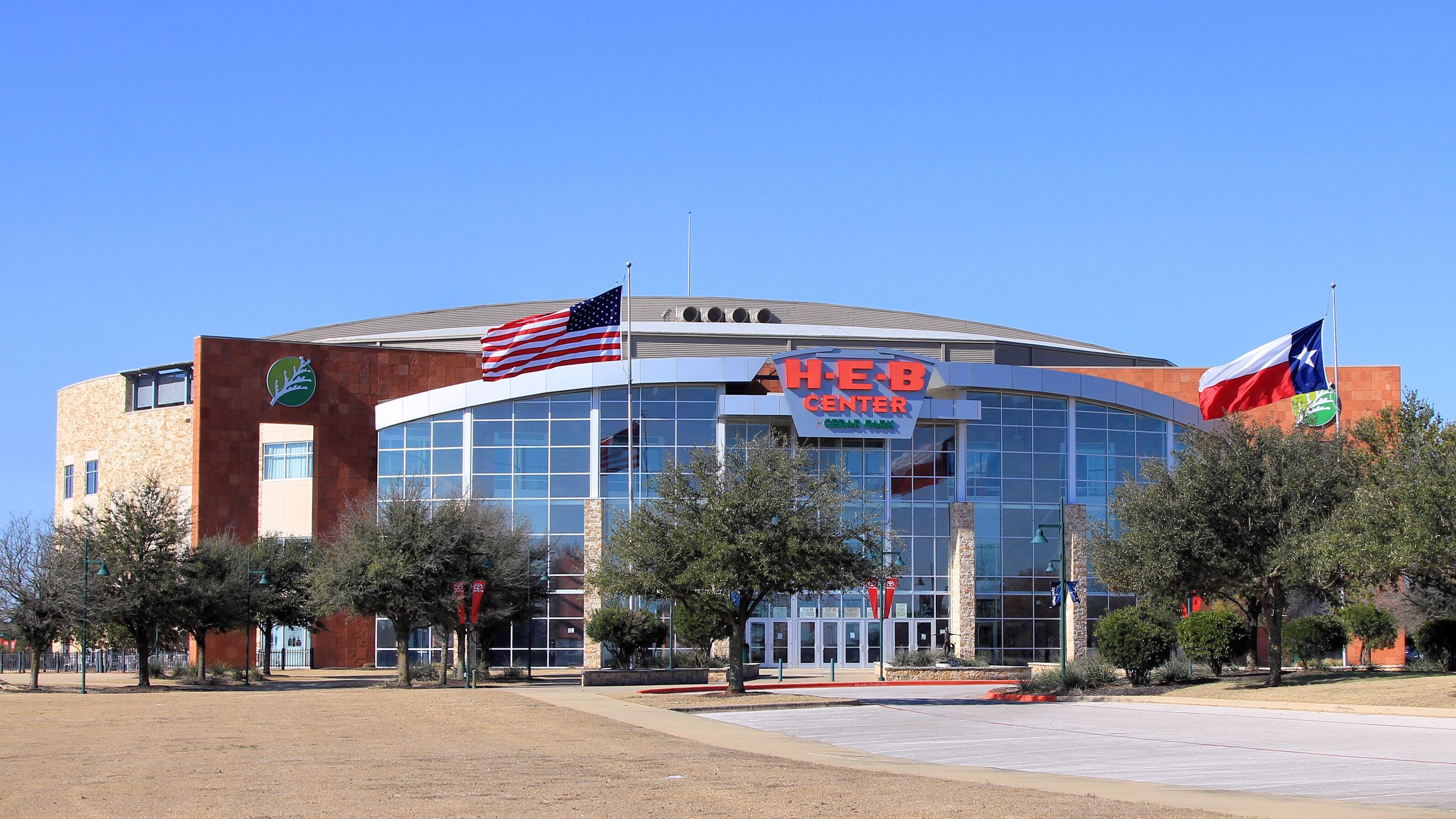 A H-E-B Center building with an American flag and a Texas state flag.