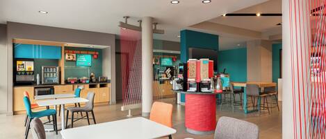 A modern restaurant with white tables and chairs, a kitchen area, and a colorful decor.