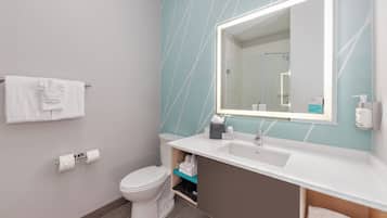 Un baño moderno con inodoro blanco, lavamanos con espejo y un perchero con toallas.