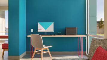A modern office space with teal walls, a desk, a chair, and a couch.