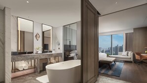 A modern bathroom with a freestanding bathtub, a vanity with a large mirror, and a city view through the window. - Intercontinental Zhengzhou by IHG (Zhengzhou)
