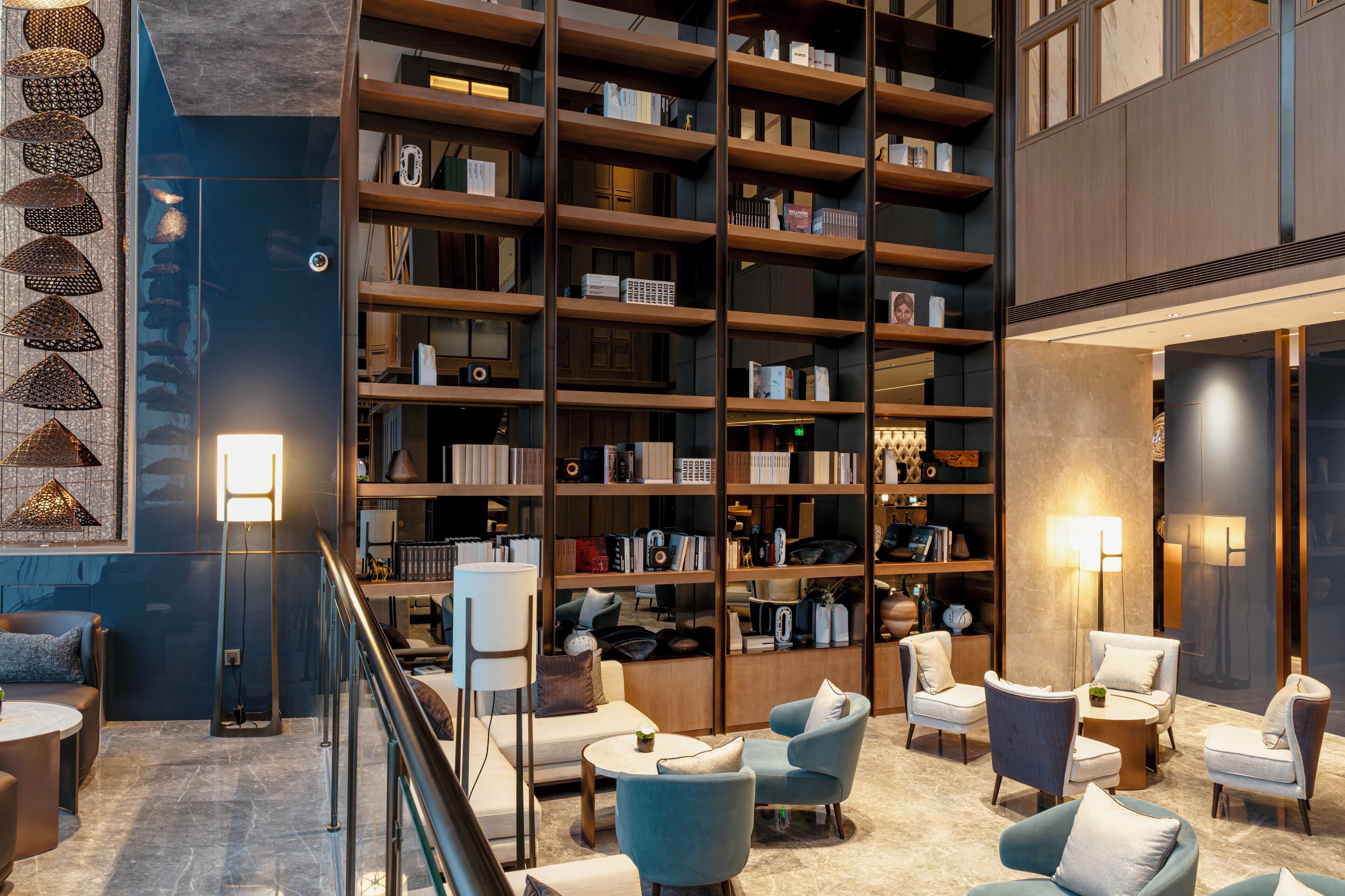 A modern library with bookshelves, seating areas, and decorative lighting.