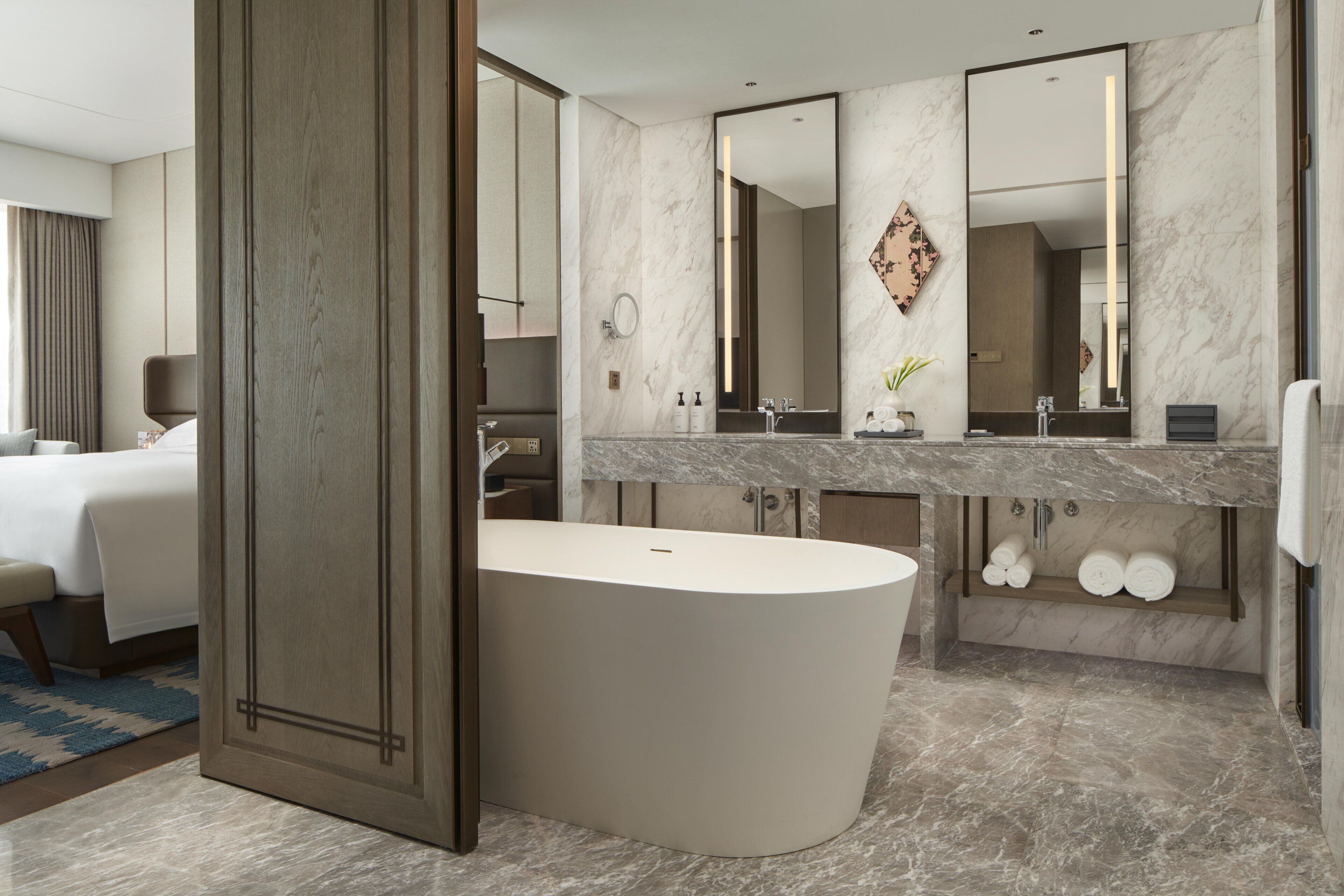 A modern bathroom with a freestanding bathtub, a large mirror, and a vanity with a marble countertop.