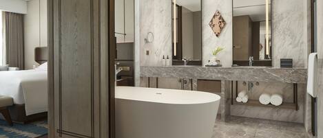 A modern bathroom with a freestanding bathtub, a large mirror, and a vanity with a marble countertop.