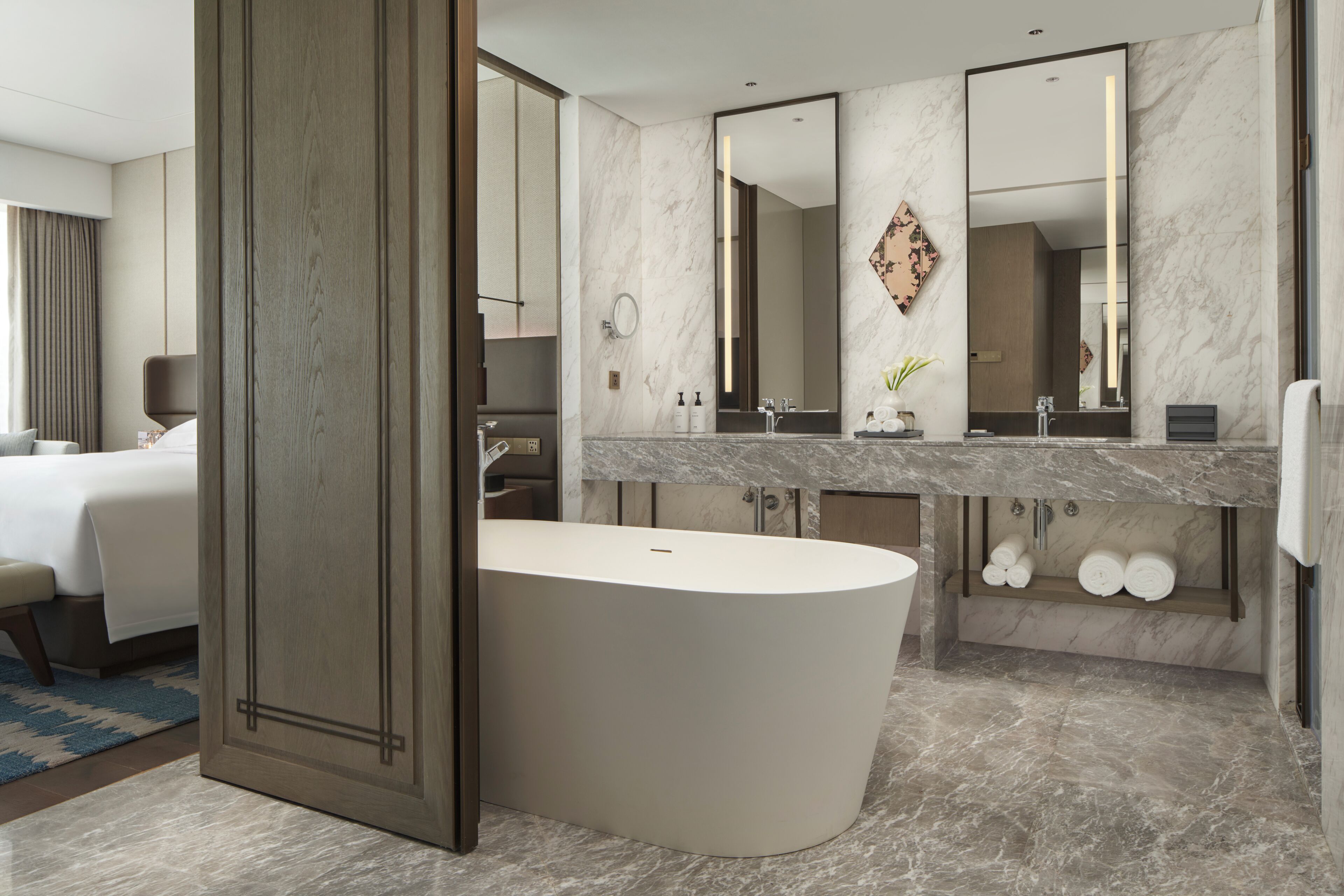 A modern bathroom with a freestanding bathtub, a large vanity with a mirror, and a shower area.
