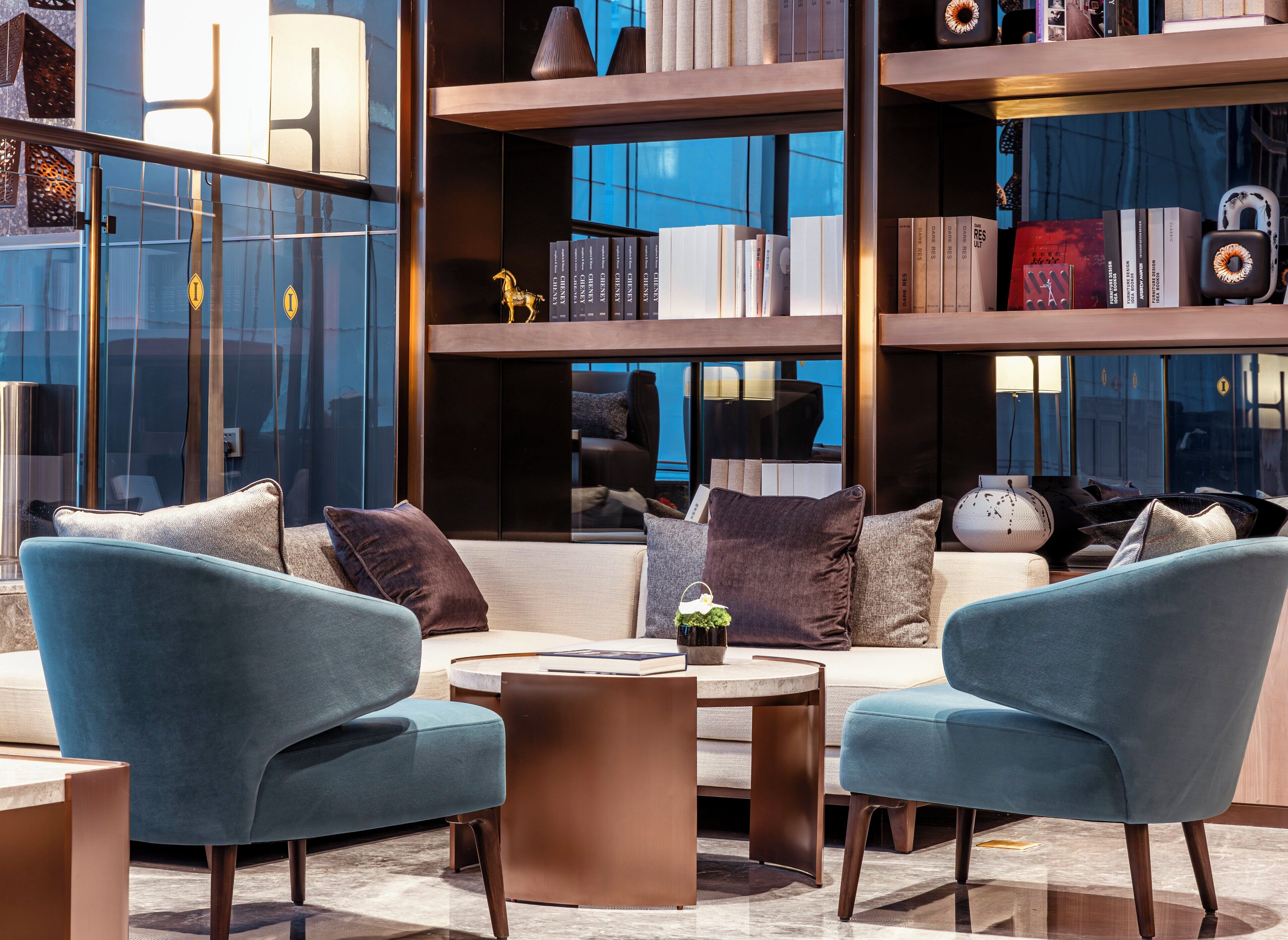 Un salon moderne comprenant un ensemble de canapés, une table basse et une bibliothèque remplie de livres et d’objets décoratifs.