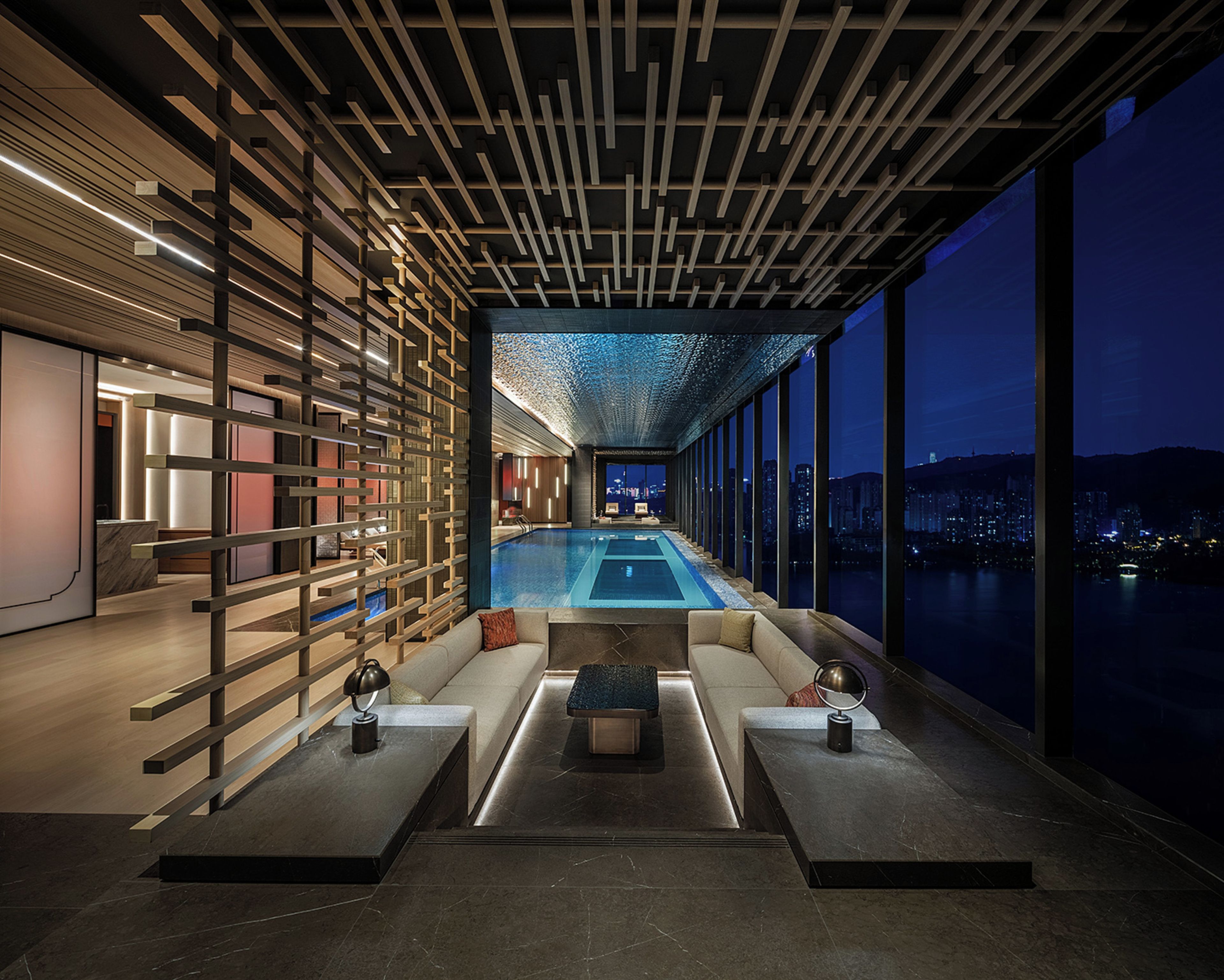 A modern indoor pool area with a view of the city at night.