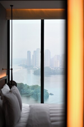 A hotel room with a large window overlooking a cityscape and a river. - Hotel Indigo Changsha Meixi Lake by IHG (Changsha)