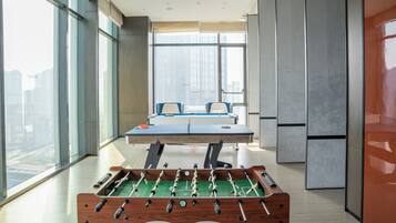 Una habitación moderna con mesa de fútbol de mesa, ventanas amplias y vistas a la ciudad.