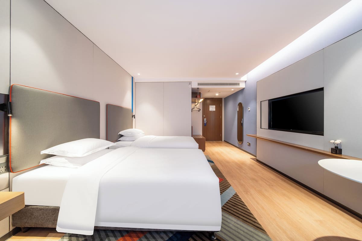 A modern hotel room with a large bed, a TV, a bathroom, and a walk-in closet.
