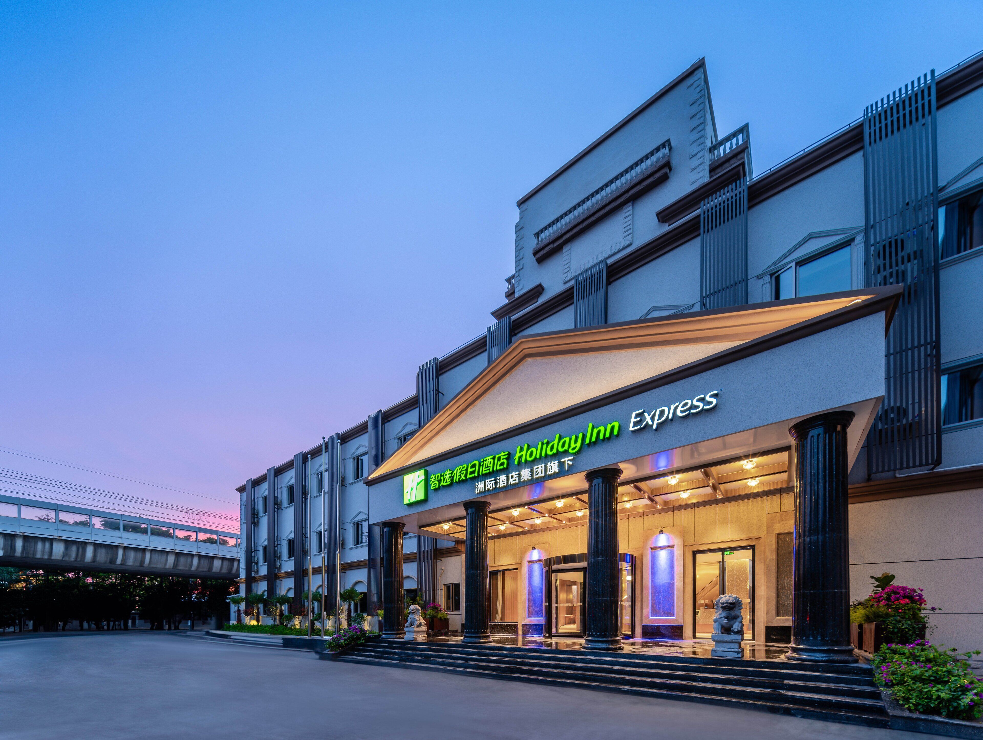 A Holiday Inn Express hotel with a modern facade, large columns, and a well-lit entrance.