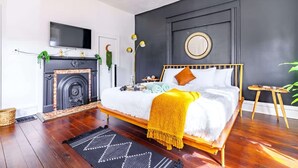 A bedroom with a bed, a fireplace, a television, and a round mirror on the wall. - Jungle House Luxury Stays - Downtown Chillicothe (Chillicothe)