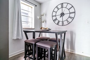 A room with a table, three stools, a wall clock, a window with curtains, and a floor lamp. - Jungle House Modern Lofts – Arena District & Short North (Columbus)