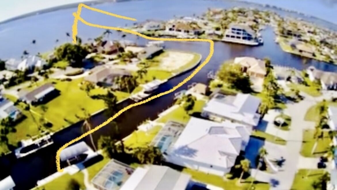 An aerial view of a residential area with houses, a river, and boats.