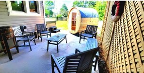 Relax in a serene outdoor space with a rustic charm, featuring a barrel structure, comfortable seating, and a fence.