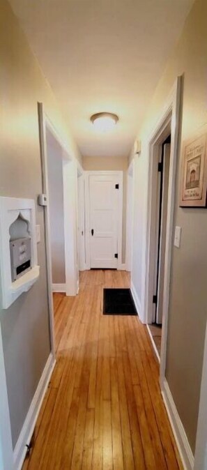 Leading to a space, this hallway features a door at the end and a convenient shelf for storage.