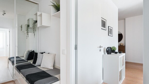 Un dormitorio moderno con una cama, un armario y una mesita con objetos decorativos.