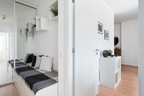 A modern bedroom with a bed, a wardrobe, and a small table with decorative items. - GuestReady - Casa da Música Comfort (Porto)