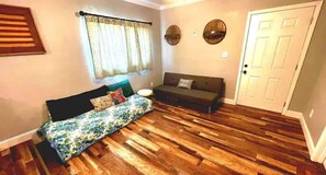 Relax in a cozy space with a plush bed, dark sofa, and stylish mirrors.