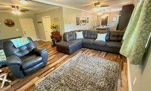 Relax in comfort on the large leather sofa, surrounded by a plush area rug and a cozy armchair.