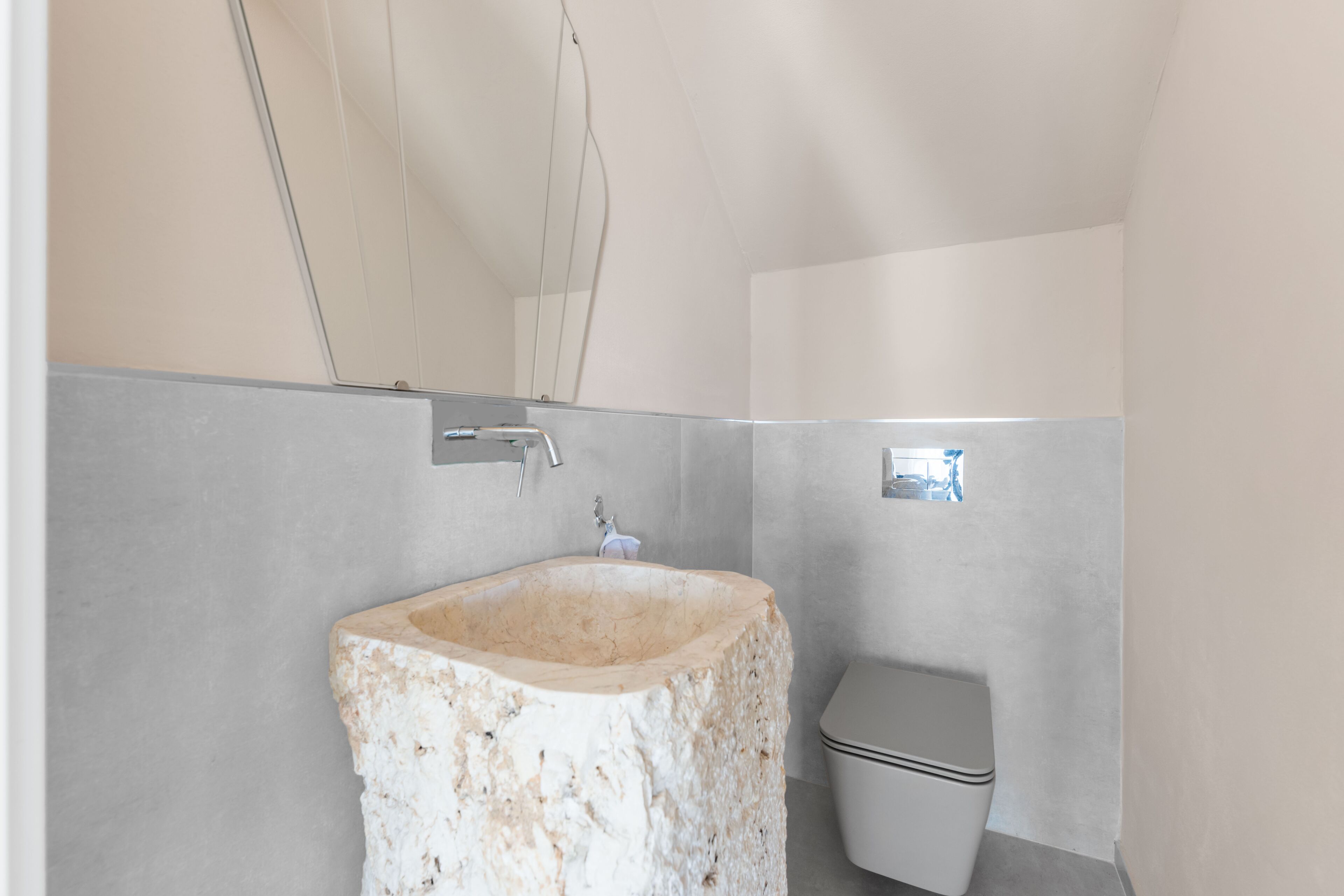 Une salle de bain avec un lavabo en pierre, des toilettes et un miroir.