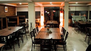 Un restaurante con varias mesas y sillas de madera, piso de baldosas y una decoración interior moderna.
