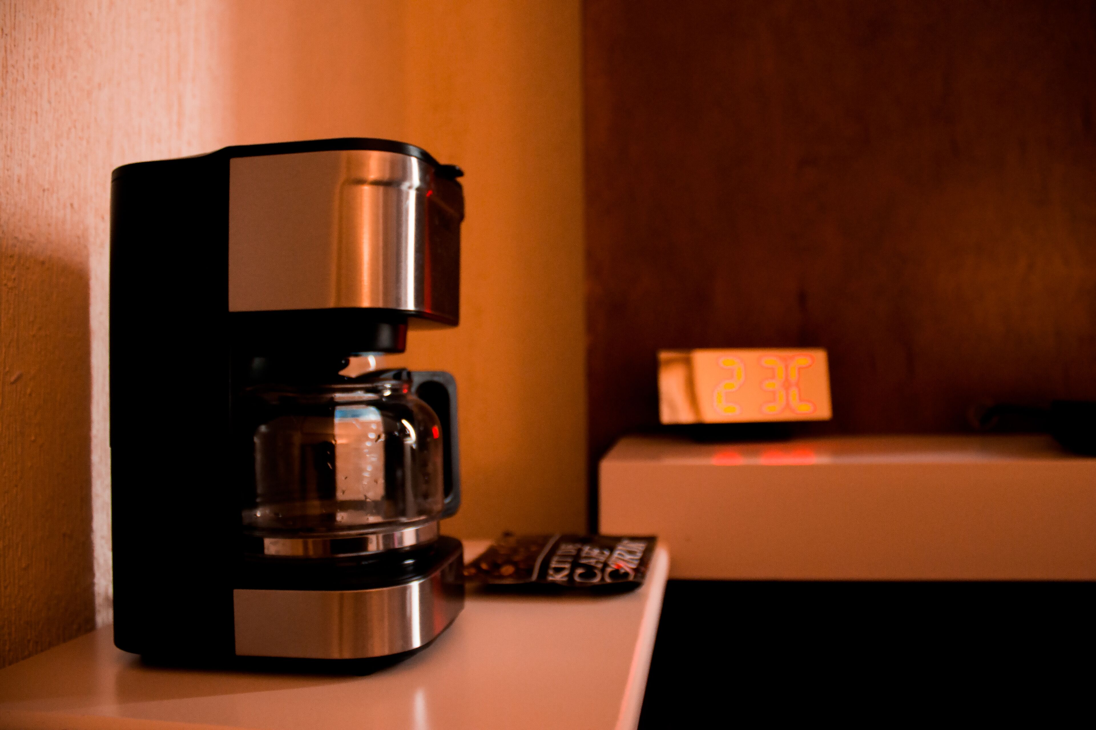 A coffee maker on a counter with a digital clock displaying the time.