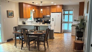 Una cocina moderna con armarios de madera, una isla central y un comedor con sillas.