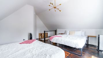 Een moderne slaapkamer met twee bedden, een houten vloer, een schuine kap en een bijzondere kroonluchter.