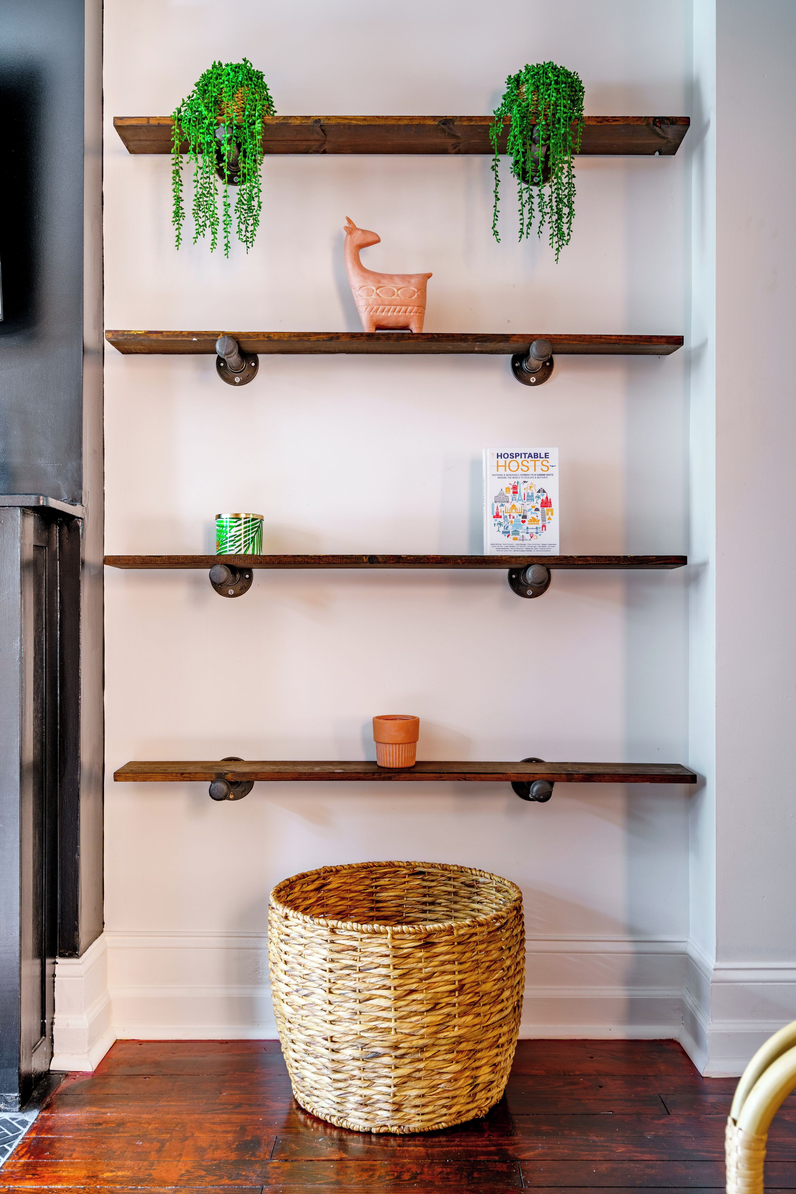 Une étagère murale agrémentée d’objets décoratifs et d’un panier en osier.