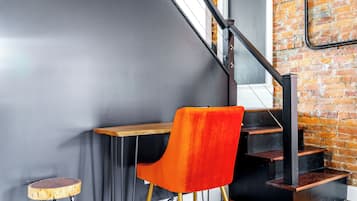 Una escalera con barandilla negra, un escritorio de madera y una silla roja.