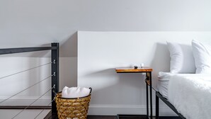 A bedroom with a bed, a small wooden nightstand, a wicker basket, and a metal ladder. - Jungle House Urban Lofts - Short North & Convention Center (Columbus)