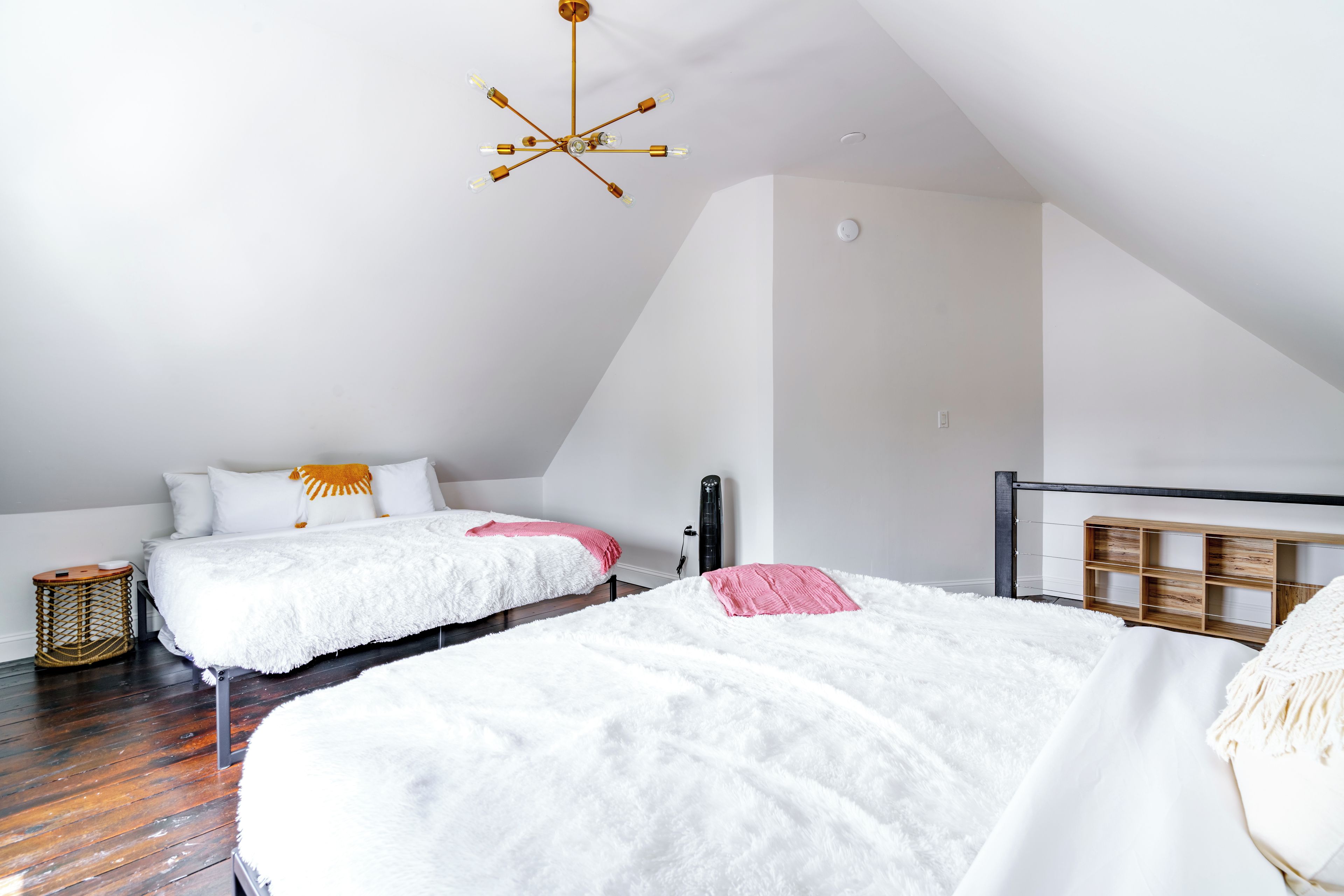 A bedroom with two beds, a ceiling fan, and a wooden headboard.