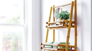 A bamboo shelf with folded towels and a potted plant against a white wall. - Jungle House Urban Lofts - Short North & Convention Center (Columbus)