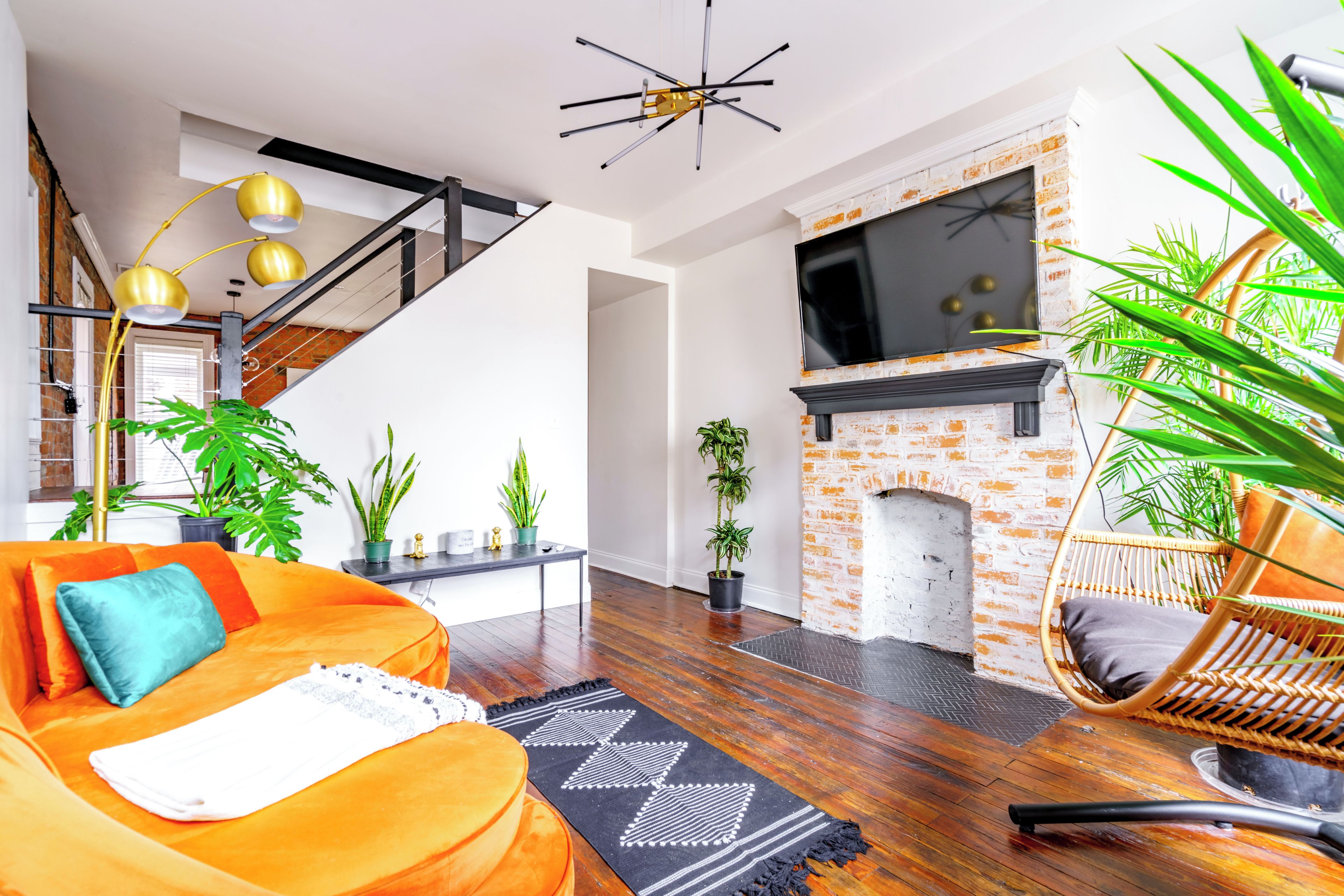 Een moderne woonkamer met een bank, een open haard, een televisie en een trap.