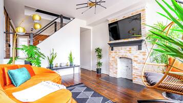 Een moderne woonkamer met een bank, een open haard, een televisie en een trap.