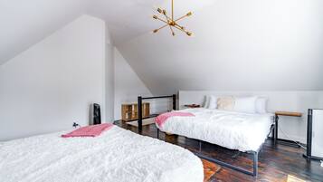 A modern bedroom with two beds, a wooden floor, a sloped ceiling, and a unique chandelier.