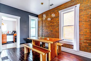 A modern kitchen with a brick wall, wooden table, and bench. - Jungle House Urban Lofts - Short North & Convention Center (Columbus)