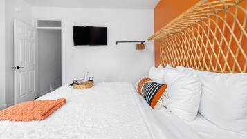 A bedroom with a bed, a television, a basket, and a door.