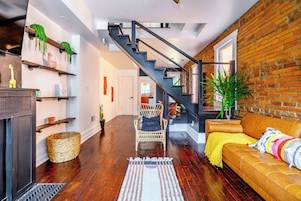 A modern living room with a staircase, wooden flooring, a sofa, and a chair.