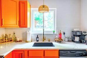 A kitchen with a white countertop, a black sink, and orange cabinets. - Jungle House Urban Lofts - Short North & Convention Center (Columbus)