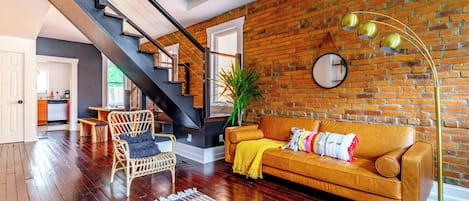 A modern living room with a staircase, a sofa, and a dining area.