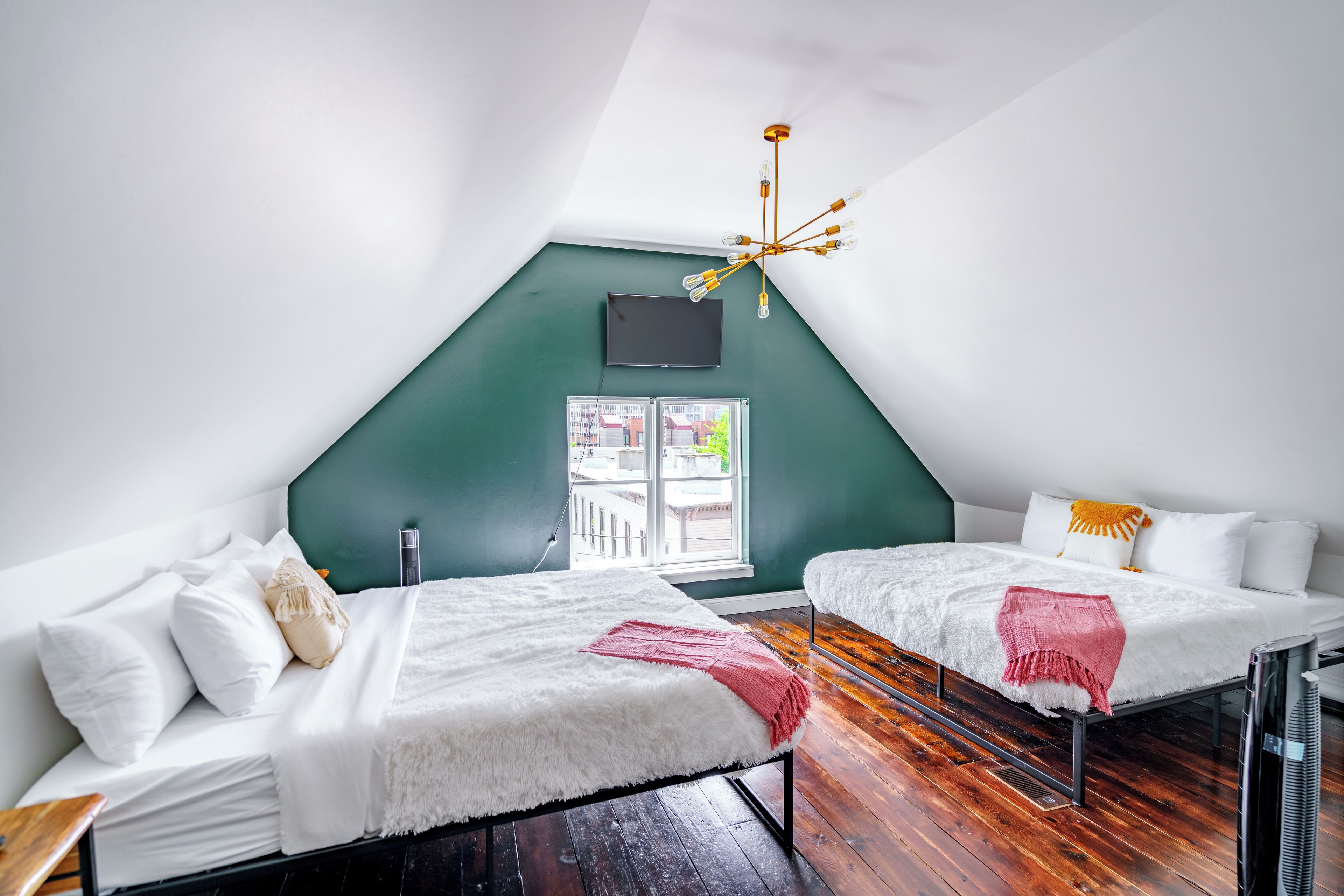 Quarto com duas camas, televisão, lustre e janela com vista.
