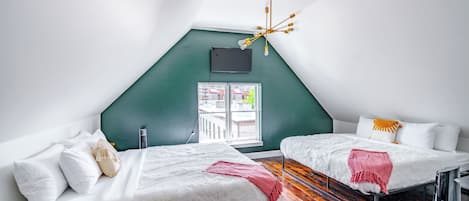 Une chambre avec deux lits, une télévision, un lustre et une fenêtre donnant sur un beau paysage.
