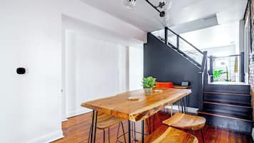 A modern interior with a wooden dining table, chairs, a staircase, and a plant.