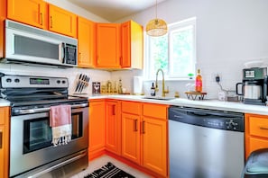 Una cucina con mobili arancioni, forno a microonde, piano cottura e lavastoviglie.