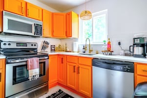 Una cucina con mobili arancioni, forno a microonde, piano cottura e lavastoviglie.
