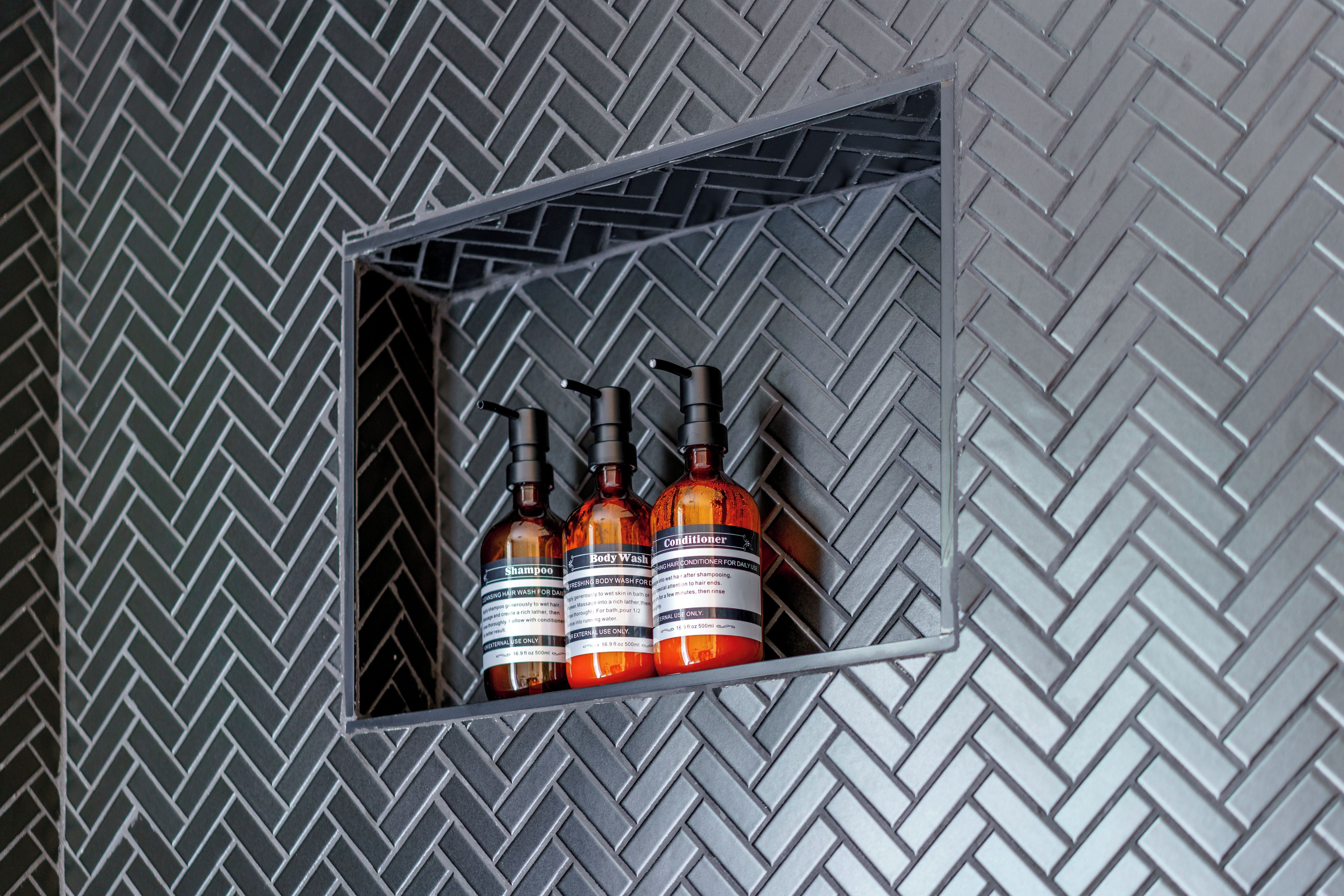 A metal shelf with three bottles of body wash and conditioner.